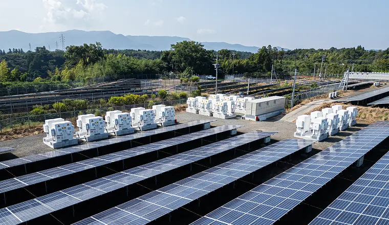 太陽光パネルが並ぶ発電所内に、蓄電池コンテナや関連設備が設置されている様子。