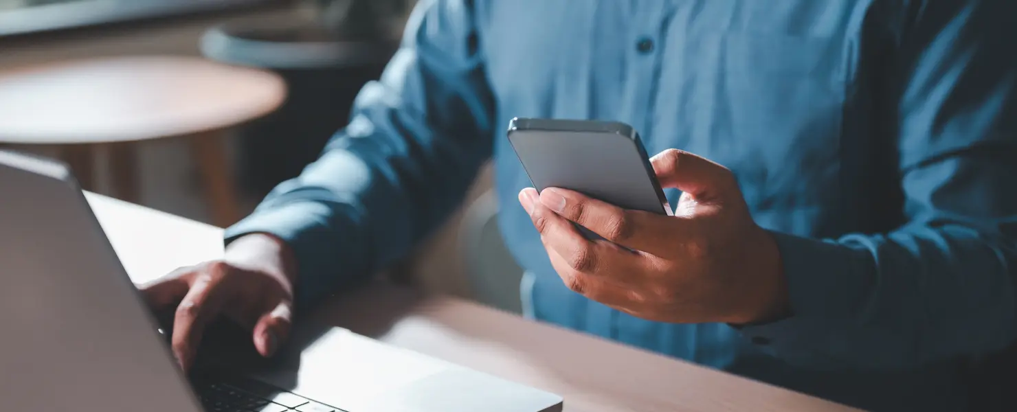 デスクでノートパソコンとスマートフォンを操作している様子
