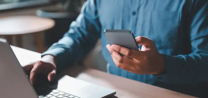 デスクでノートパソコンとスマートフォンを操作している様子