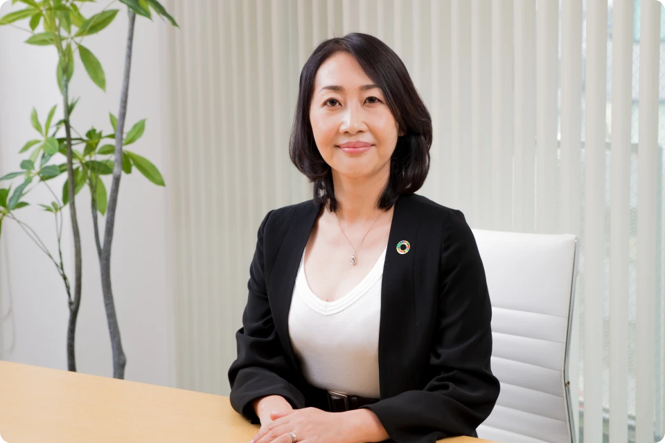 オフィスで机に手を組み微笑む様子
