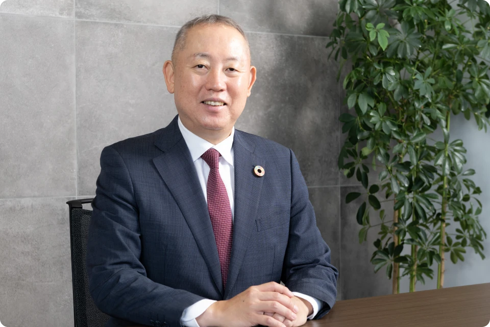 スーツ姿で正面を向いて微笑んでいる社長